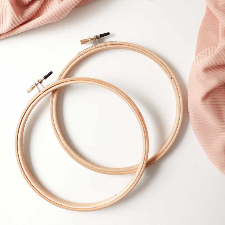Two wooden embroidery hoops overlapping, showing the smooth beechwood rings and hardware