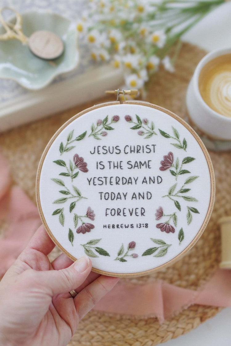 Hand holding the finished Hebrews 13:8 hoop