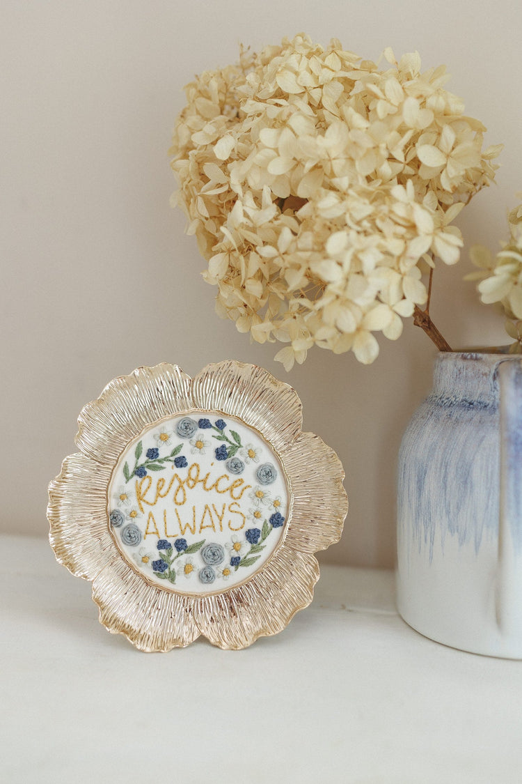 Finished Rejoice Always piece beside a vase of dried hydrangea