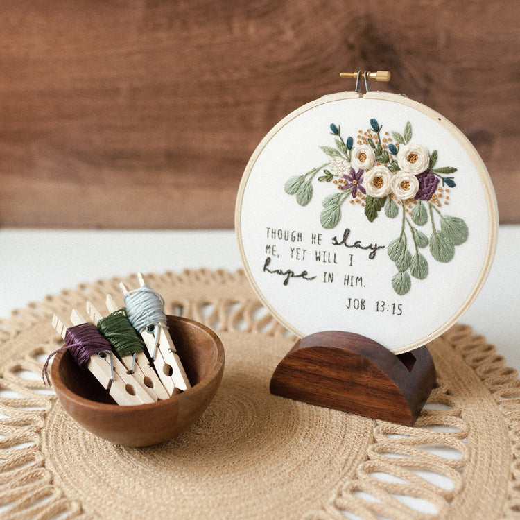 Job 13:15 embroidery hoop displayed on a walnut stand with floss in a wooden bowl