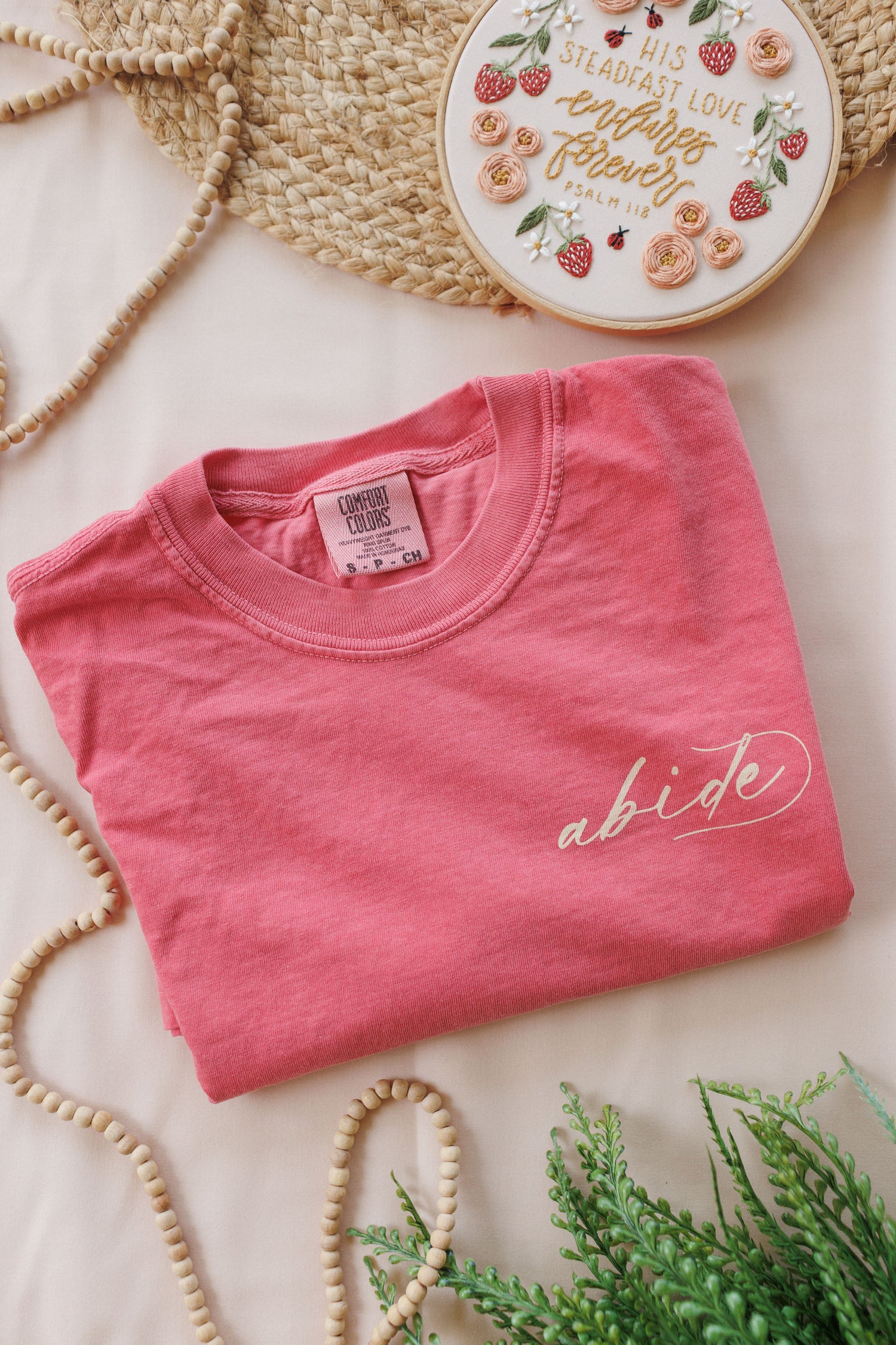 Back design of the His Steadfast Love Psalm 118 t-shirt — hand-lettered Scripture framed by florals, strawberries and needle-and-thread