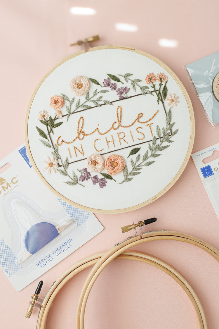 Abide in Christ embroidery hoop with a DMC needle threader and two extra 6-inch hoops