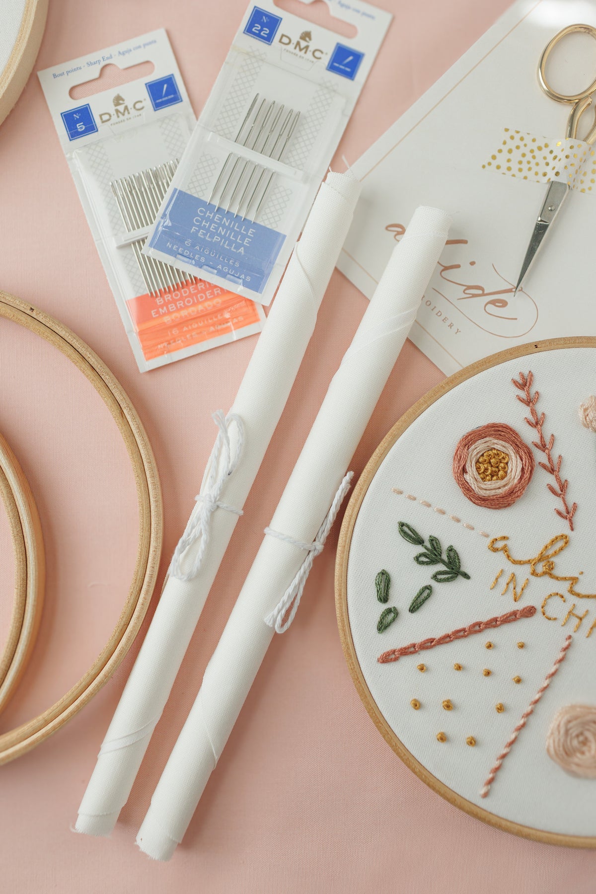 Snow fabric, DMC needles and gold scissors beside the 17-stitch practice hoop