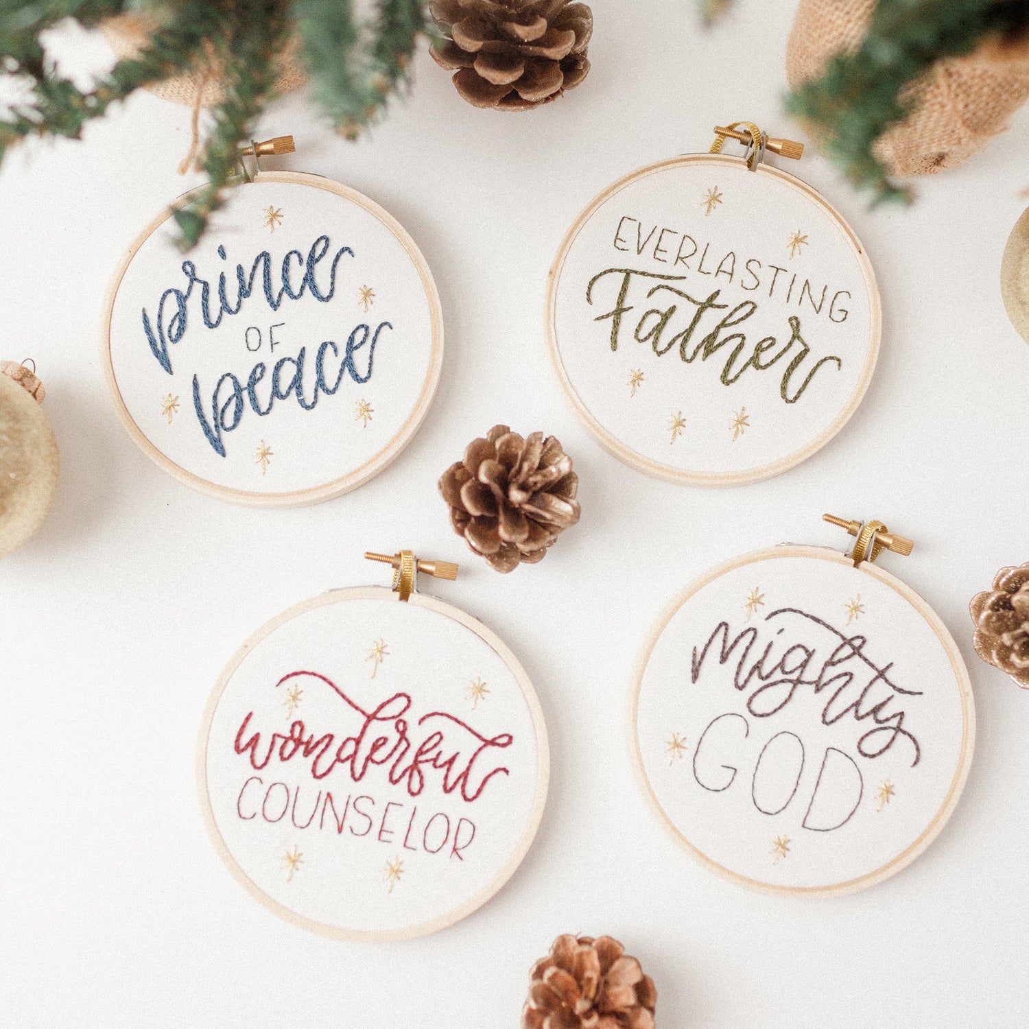 All four Names of Jesus Advent ornaments — Wonderful Counselor, Mighty God, Everlasting Father, Prince of Peace — styled with pine and pinecones