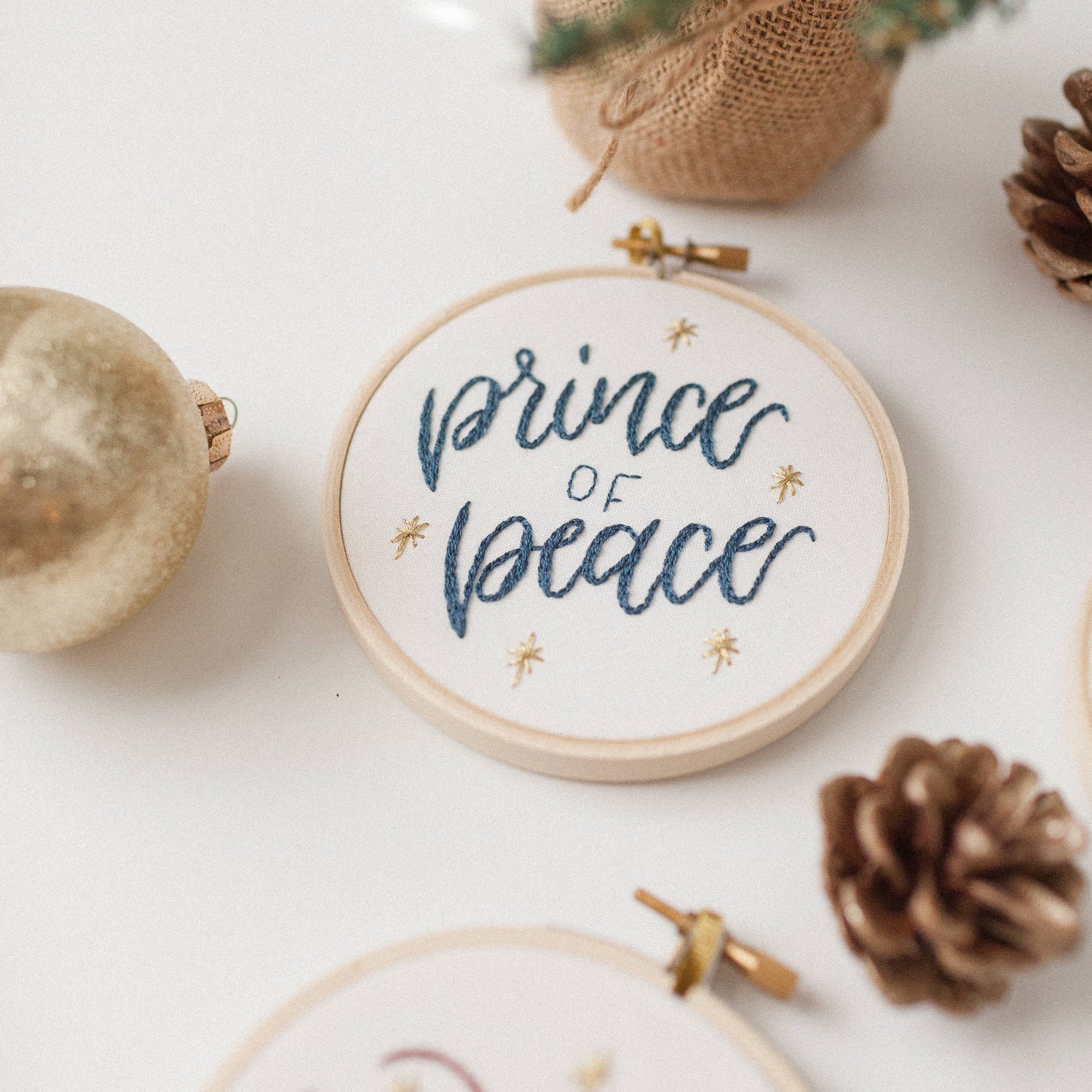 Close-up of the Prince of Peace ornament stitched in navy with gold stars