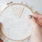 Hands stitching the 17-stitch practice sampler in progress