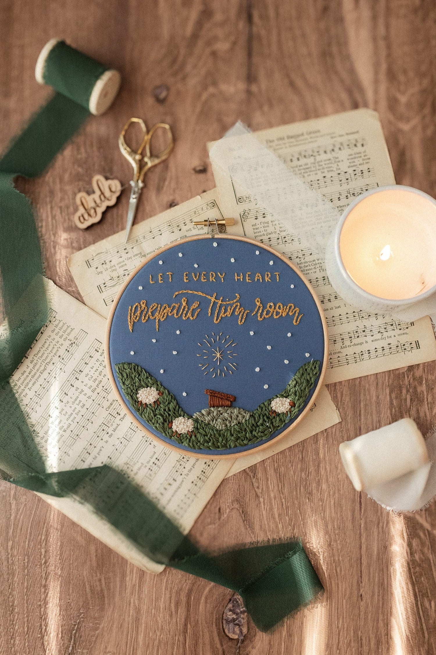 Advent embroidery hoop on a wood table with a lit candle