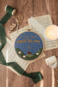 Advent embroidery hoop on a wood table with a lit candle