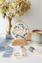 Rejoice Always hoop displayed as decor with pottery and dried florals