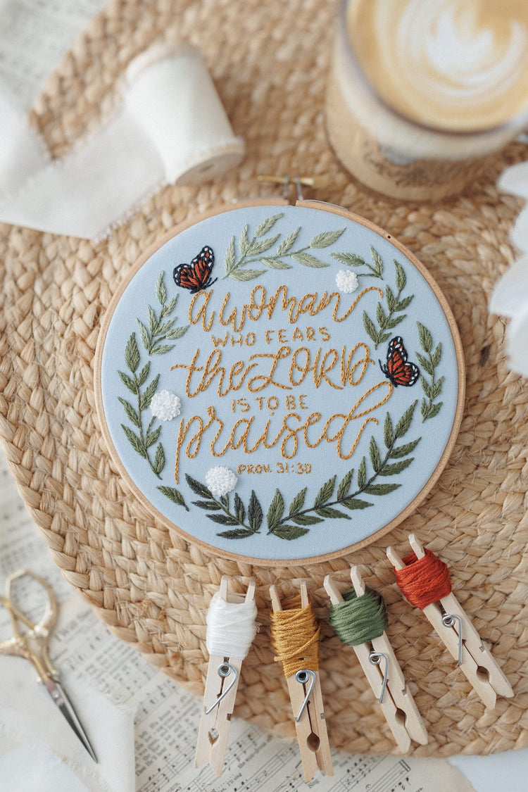 Proverbs 31 embroidery hoop with floss bobbins on a woven placemat