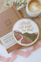 Christ Will Hold Me Fast hoop beside a prayer journal and latte