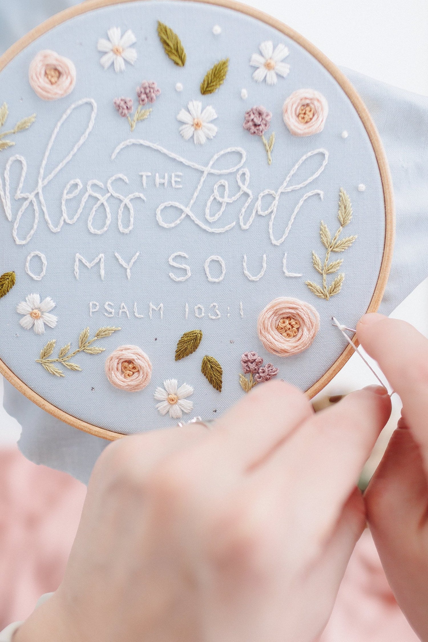 Hands stitching the Bless the Lord O My Soul design in progress
