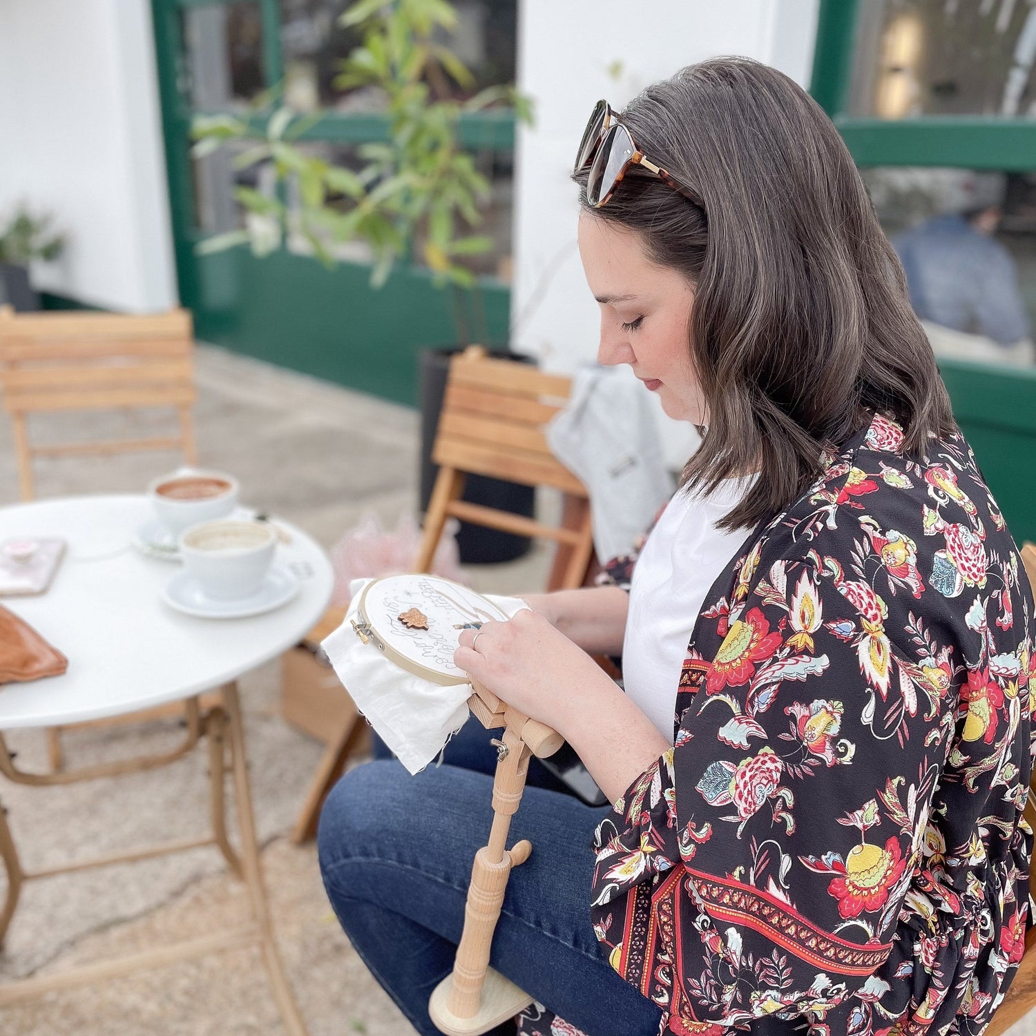 Embroidery hoop stand in use at a cafe table — hands-free stitching while seated
